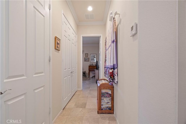 corridor with baseboards, visible vents, a textured wall, and ornamental molding