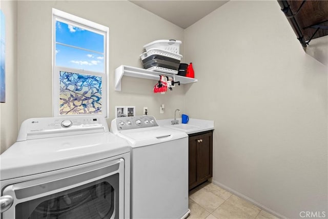 laundry area featuring light tile patterned floors, baseboards, cabinet space, separate washer and dryer, and a sink