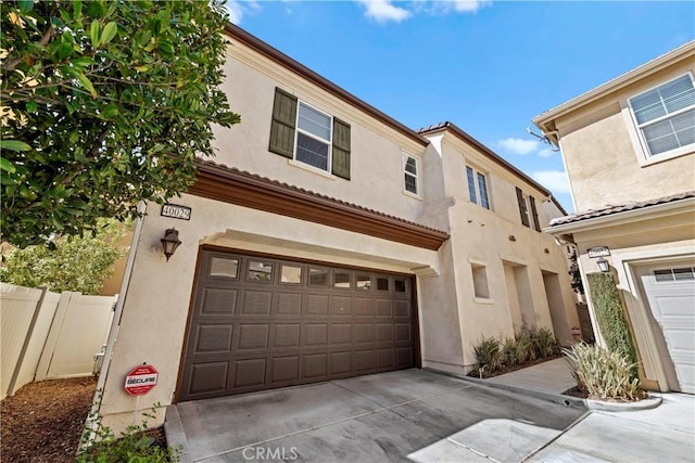 townhome / multi-family property featuring stucco siding, a garage, concrete driveway, and fence