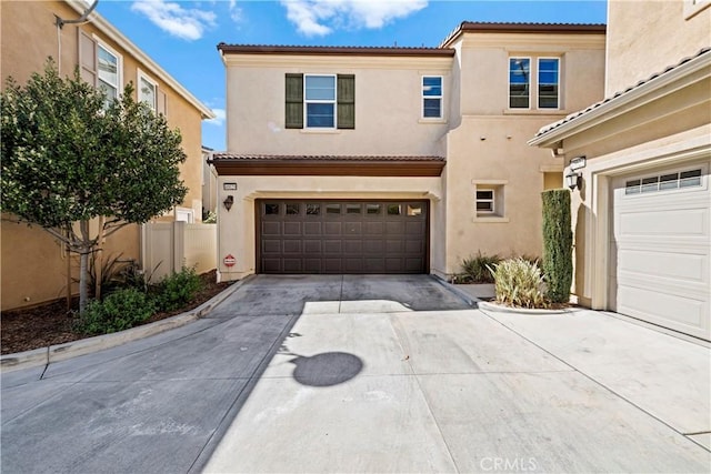 mediterranean / spanish-style home with fence, stucco siding, concrete driveway, a garage, and a tile roof