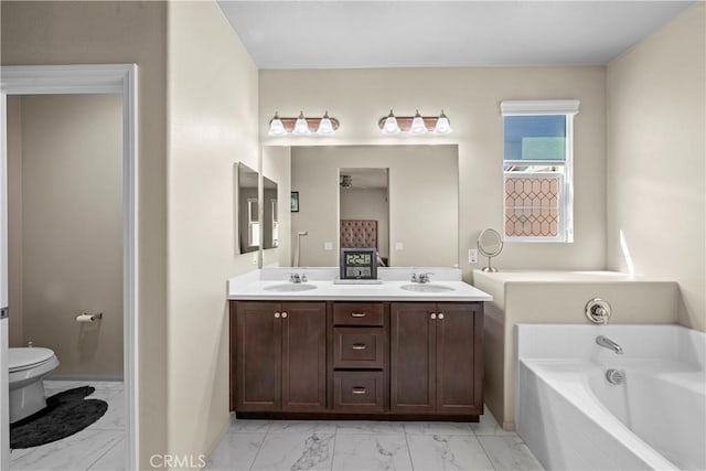 full bath with toilet, marble finish floor, a sink, double vanity, and a bath