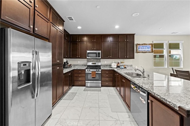 kitchen with visible vents, a peninsula, marble finish floor, stainless steel appliances, and a sink