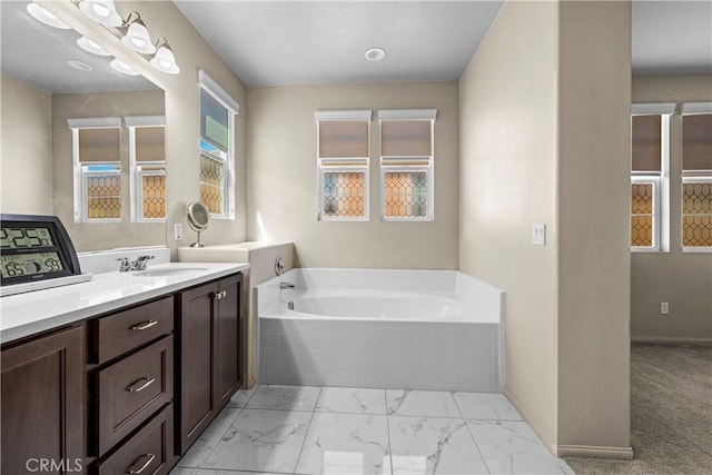 full bathroom with baseboards, a garden tub, marble finish floor, and vanity