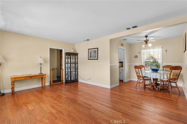 dining space featuring visible vents, a ceiling fan, baseboards, and wood finished floors