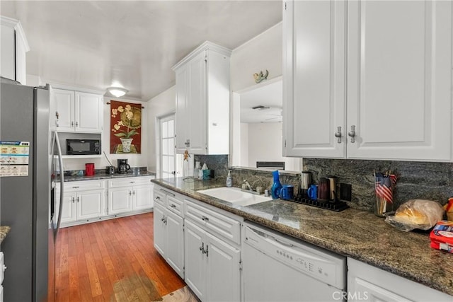 kitchen with black microwave, dishwasher, decorative backsplash, stainless steel refrigerator with ice dispenser, and white cabinets