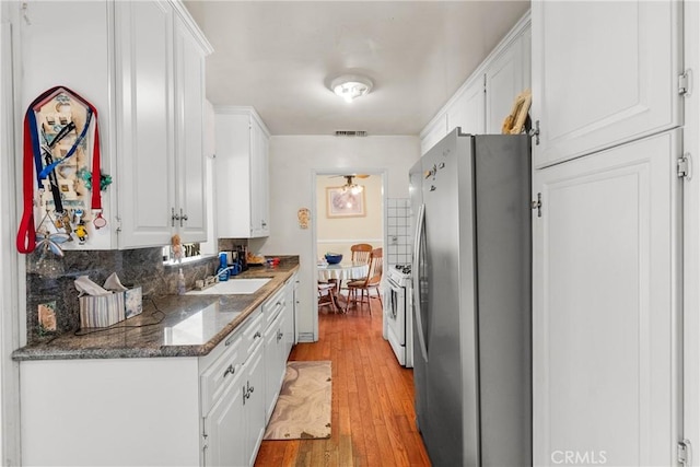 kitchen with light wood-style flooring, white gas stove, a sink, freestanding refrigerator, and white cabinets