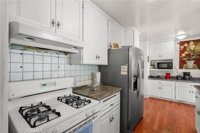 kitchen featuring black microwave, under cabinet range hood, white gas range oven, stainless steel fridge, and white cabinetry