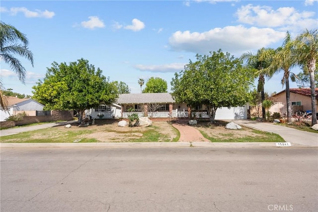 view of front facade featuring a garage, a porch, concrete driveway, and fence