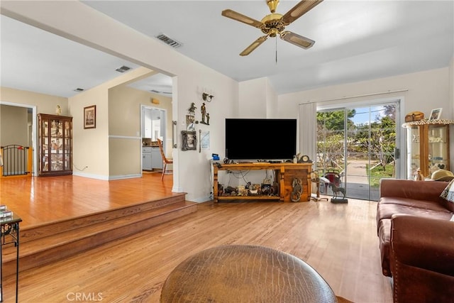 living area featuring visible vents, baseboards, a ceiling fan, and wood finished floors