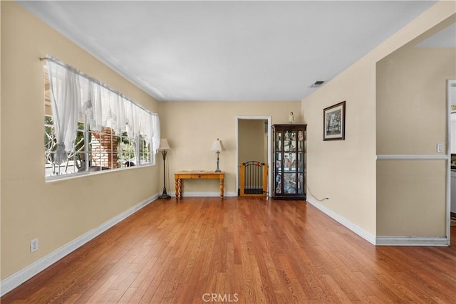 spare room featuring visible vents, baseboards, and wood finished floors