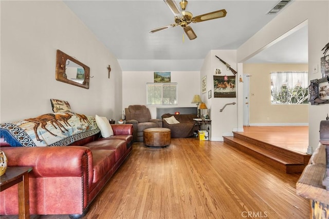 living area with stairway, a ceiling fan, wood finished floors, visible vents, and baseboards