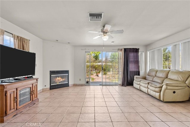 living area with light tile patterned floors, visible vents, a wealth of natural light, and a glass covered fireplace