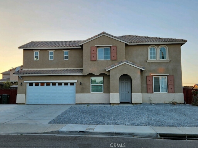 view of front of property featuring fence, concrete driveway, a tile roof, stucco siding, and a garage