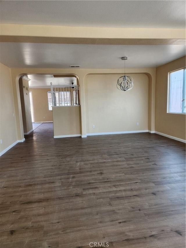 interior space with plenty of natural light, baseboards, arched walkways, and dark wood-style flooring