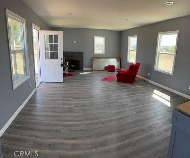 unfurnished room with recessed lighting, a brick fireplace, baseboards, and wood finished floors