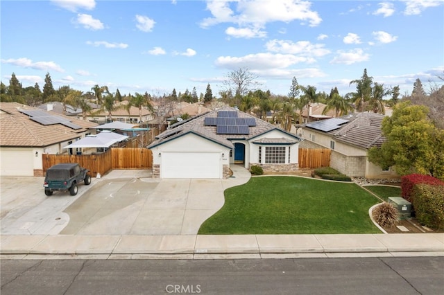 view of front of property with fence, solar panels, an attached garage, a front lawn, and stone siding