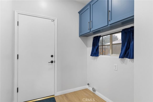 laundry room featuring cabinet space, baseboards, and light wood-style floors