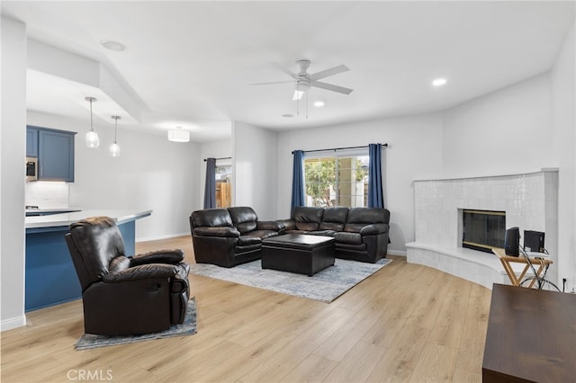 living area featuring recessed lighting, baseboards, a tile fireplace, and light wood finished floors