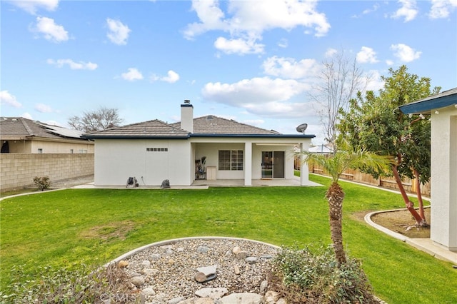 back of house featuring stucco siding, a chimney, a yard, a fenced backyard, and a patio area