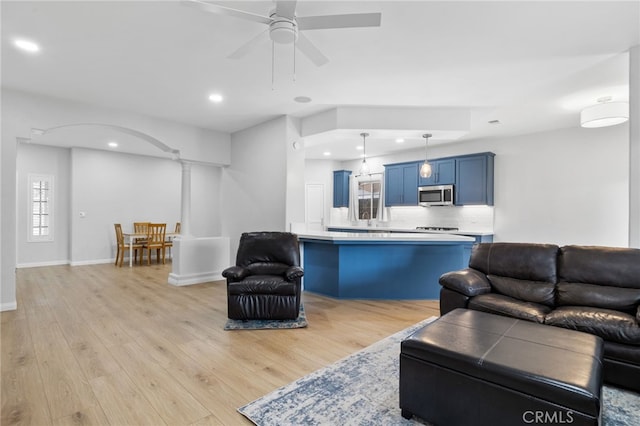 living area featuring baseboards, ceiling fan, recessed lighting, light wood-style flooring, and arched walkways