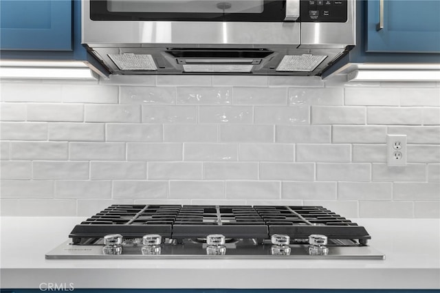 details featuring blue cabinetry, tasteful backsplash, and appliances with stainless steel finishes