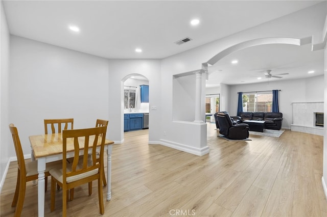 dining space featuring decorative columns, arched walkways, visible vents, and light wood-type flooring