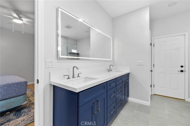 ensuite bathroom featuring a sink, baseboards, ceiling fan, and double vanity