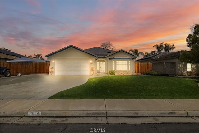 ranch-style home with stucco siding, driveway, a front lawn, fence, and a garage