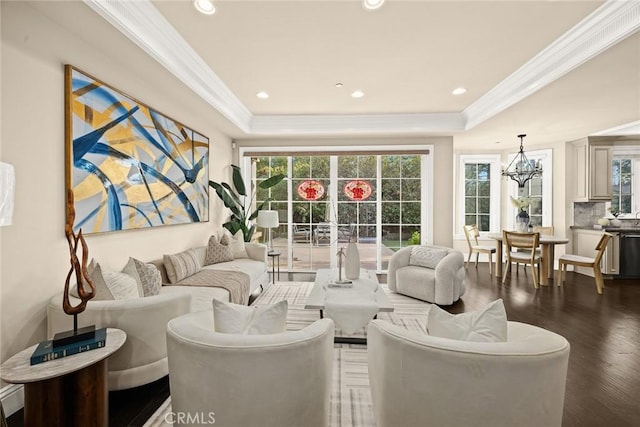 living area featuring a tray ceiling, a notable chandelier, wood finished floors, and ornamental molding