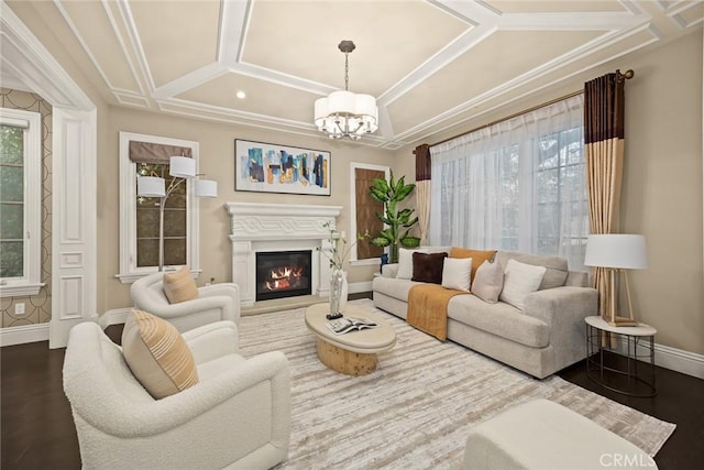 living room with dark wood-type flooring, baseboards, a glass covered fireplace, a notable chandelier, and coffered ceiling