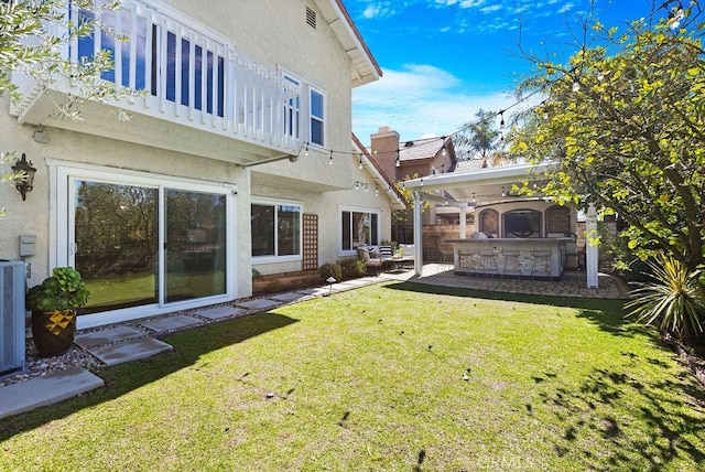 view of yard with a balcony, outdoor dry bar, and a patio area