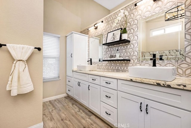 bathroom with a sink, decorative backsplash, wood finished floors, and double vanity