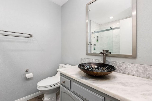 bathroom with toilet, a stall shower, wood finished floors, baseboards, and vanity