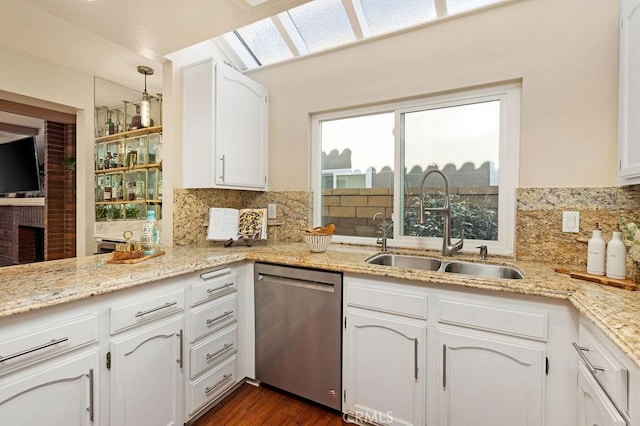 kitchen with light stone counters, white cabinetry, a sink, decorative backsplash, and dishwasher