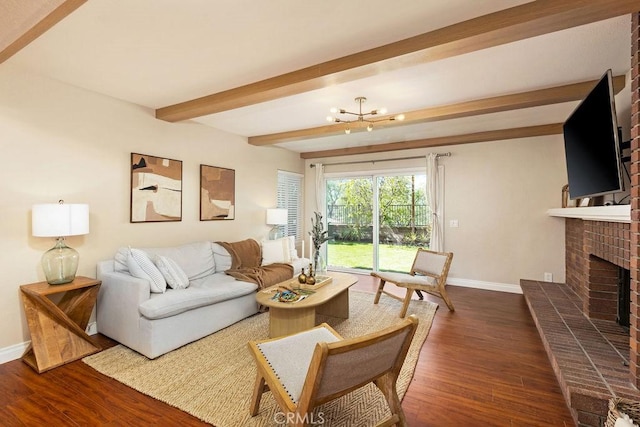 living area featuring beamed ceiling, dark wood finished floors, baseboards, a brick fireplace, and a chandelier