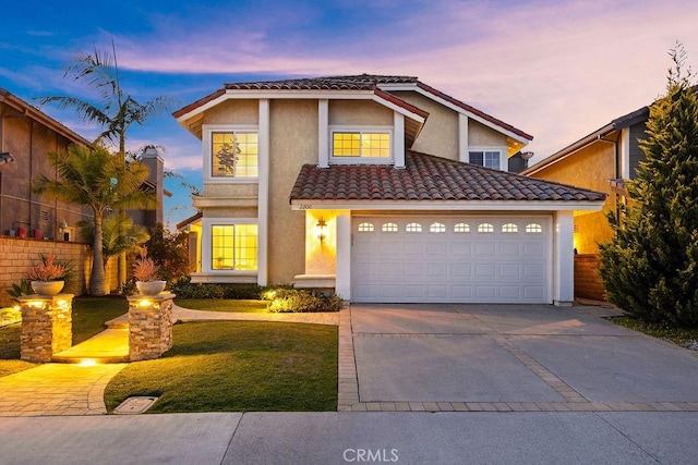 traditional home featuring a tile roof, concrete driveway, stucco siding, a yard, and an attached garage