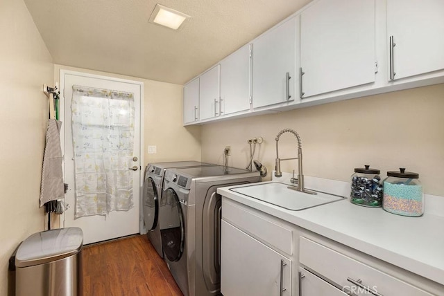 laundry room featuring washer and clothes dryer, cabinet space, dark wood-type flooring, and a sink