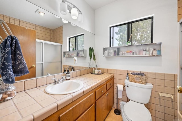 bathroom featuring a wainscoted wall, toilet, tile walls, a shower stall, and vanity