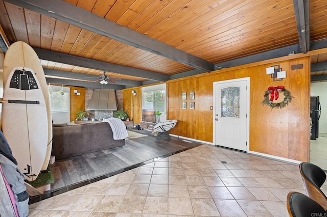 tiled foyer entrance featuring beam ceiling, wooden walls, wood ceiling, and a ceiling fan