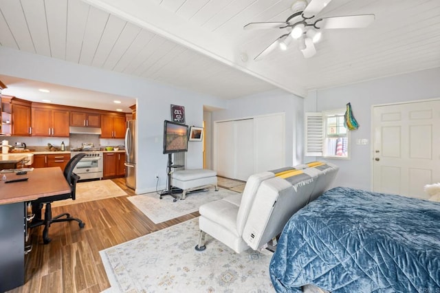 bedroom with light wood-style flooring, freestanding refrigerator, a closet, wooden ceiling, and beamed ceiling