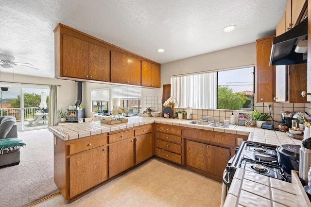 kitchen featuring a peninsula, a wood stove, brown cabinetry, and a sink