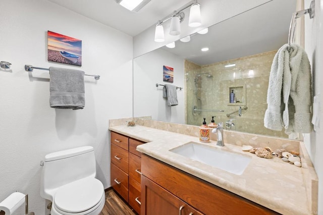 full bathroom featuring tiled shower, toilet, and vanity