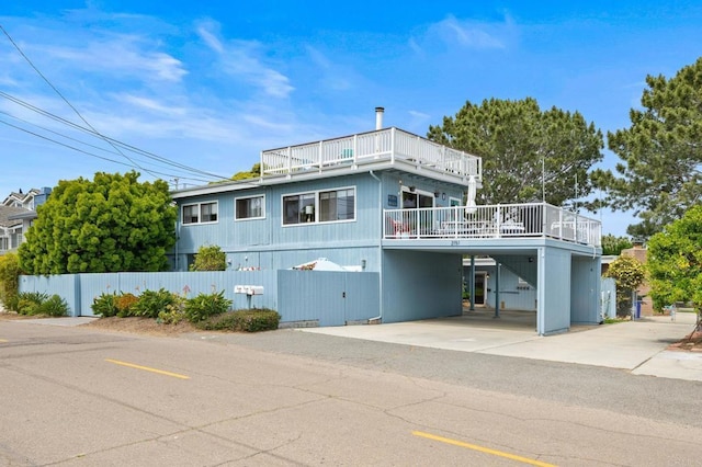 view of front of home featuring a carport, a balcony, and fence