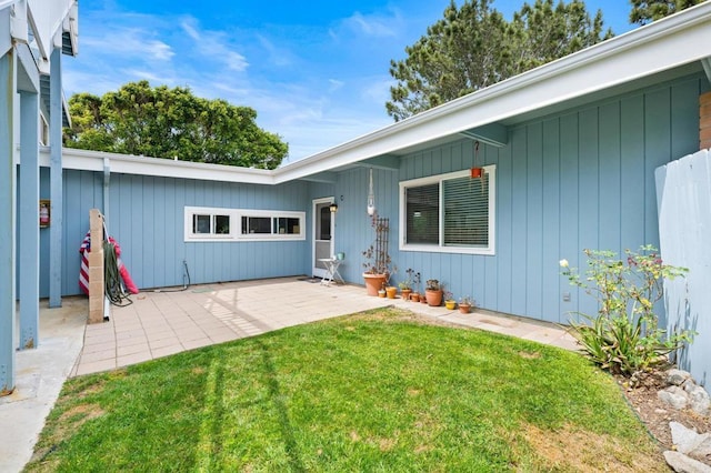 entrance to property with a lawn and a patio