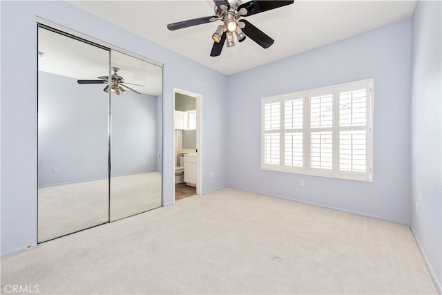 unfurnished bedroom with a closet, carpet, ceiling fan, and ensuite bathroom