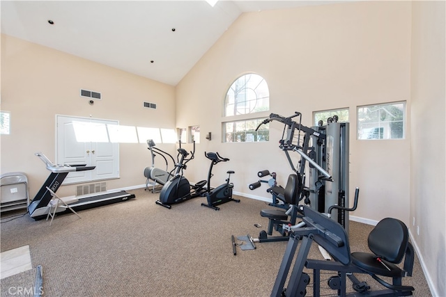 exercise room featuring visible vents, high vaulted ceiling, and baseboards