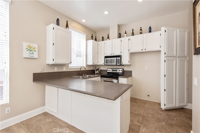 kitchen featuring a peninsula, recessed lighting, appliances with stainless steel finishes, white cabinetry, and dark countertops