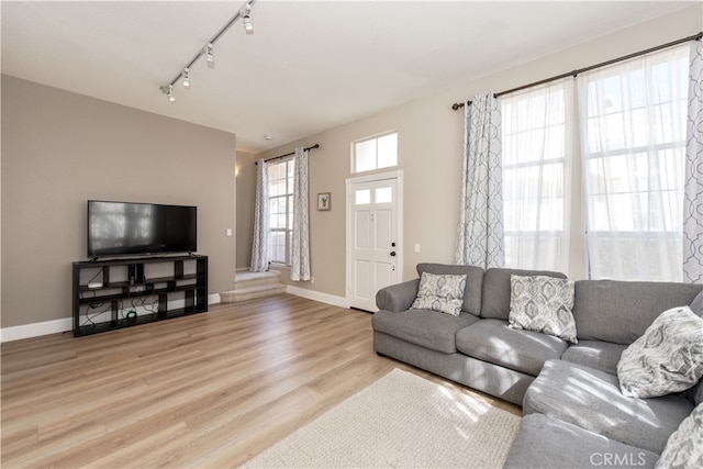 living area with track lighting, light wood-style floors, and baseboards