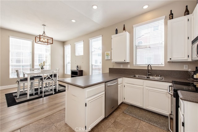 kitchen with dark countertops, white cabinetry, stainless steel appliances, and a sink