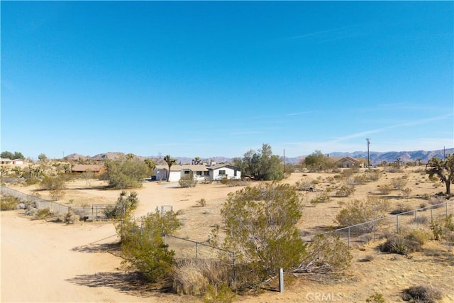 view of yard with a mountain view, a rural view, view of desert, and fence